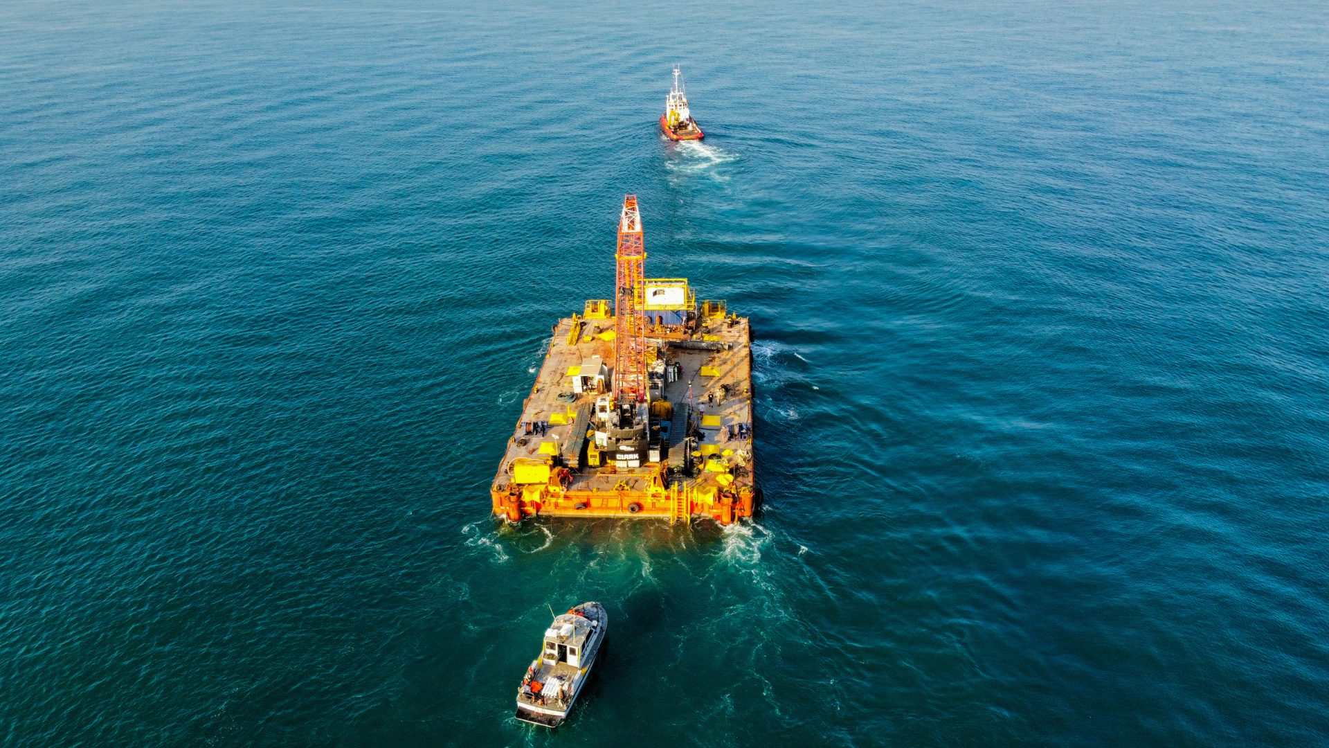 Crane barge under tow at sea, seen from above